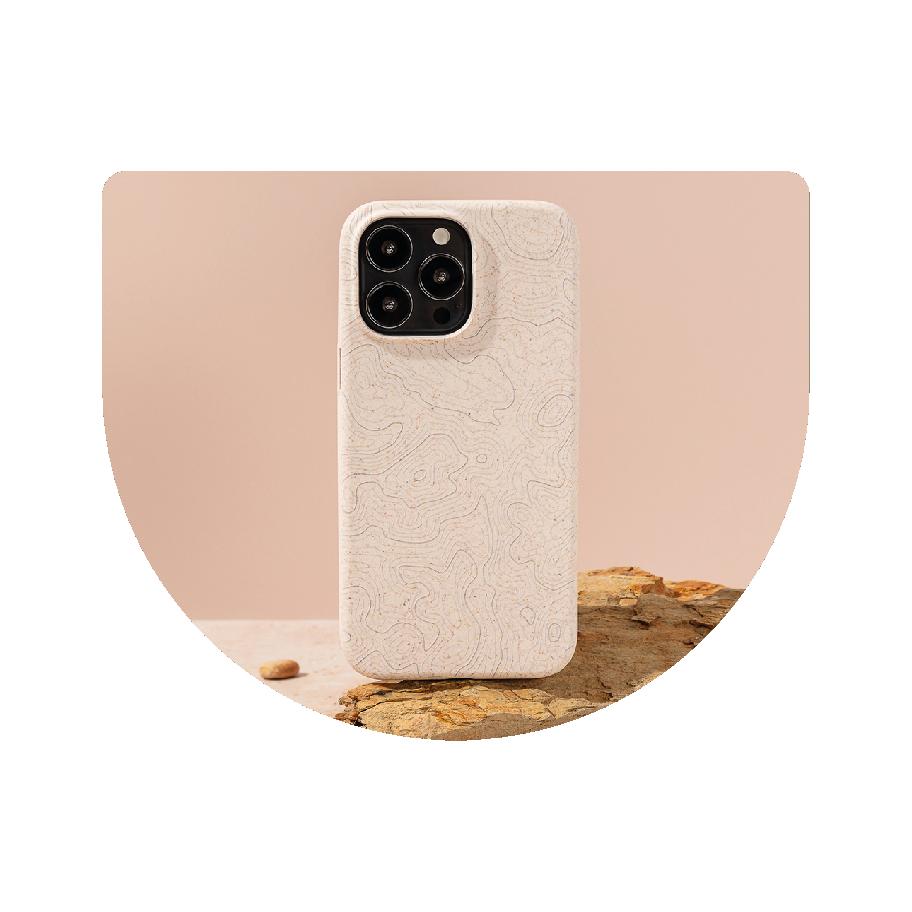 A smartphone with a beige, textured case stands on a rough-edged rock. Two smooth stones are nearby, all against a soft beige background.