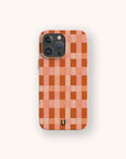 The Terracotta Watercolour Checker Eco-Friendly Phone Case features a red and pink checkerboard pattern with a small black horseshoe-shaped logo near the bottom, displayed against a plain light background.