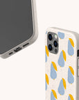 Two views of a smartphone in the Pears Biodegradable Eco-Friendly Phone Case, featuring a speckled off-white design with blue and yellow pears. One phone displays the camera and case pattern, while the other shows the screen and accessible side ports.