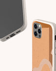 Two smartphones in beige cases featuring a tan terracotta abstract strokes design. One device displays the front screen and charging port, while the other highlights the back with triple camera lenses. Both phones are protected by Terracotta Abstract Strokes Eco-Friendly Biodegradable Phone Cases, which have a textured finish for a sustainable, eco-conscious look.