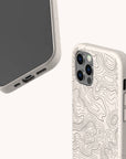 Two beige smartphones with contour line designs on their cases are shown. One phone displays the screen and ports, while the other highlights the rear cameras and the engraved pattern. The phones feature the Terrain Lines Eco-Friendly Phone Case—a plastic-free accessory that combines style with sustainability.