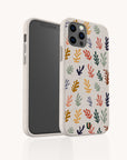 A smartphone in the Algae Eco-Friendly Phone Case, beige and made from biodegradable materials, features a vibrant abstract coral pattern in red, yellow, blue, green, and black. Shown angled to display both sides.