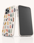 Two Algae Eco-Friendly Phone Cases in speckled white with colorful leaf patterns made from biodegradable materials. One phone displays the case’s design; the other shows its black screen, both on a white surface.