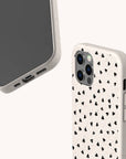 Two Black Hearts Eco-Friendly Phone Cases in beige—one showing the back with three camera lenses, and the other displaying the front with the charging port—featuring a small black heart pattern, set against a plain background.