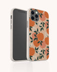 The Orange Blossom Eco-Friendly Phone Case features a beige design with orange fruit, green leaves, and white flowers. The smartphone is angled to display both the front screen and the decorative back of the case.