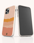 Two smartphones in speckled, off-white Valleys Eco-Friendly Phone Cases; one case features abstract horizontal stripes in peach, pink, and gold tones. The eco-friendly Valleys cases are displayed on a white reflective surface against a light background.