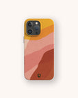 The Cliffs Eco-Friendly Phone Case features an abstract wavy design in yellow, pink, peach, and rust with a green horseshoe symbol near the bottom. Compatible with iPhone and Samsung Galaxy models.