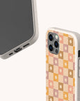 Two smartphones in speckled beige, eco-friendly Star Pink Checker phone cases; one showcases the screen, while the other displays a pastel checkered floral pattern in pink, peach, and brown hues on the back. These plant-based Star Pink Checker Eco-Friendly Phone Cases are available for both iPhone and Samsung Galaxy models.