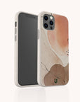 The Pink and Brown Watercolour Eco-Friendly Phone Case features abstract watercolor designs in peach, brown, and cream tones with subtle black lines and a small green "U" logo at the bottom.