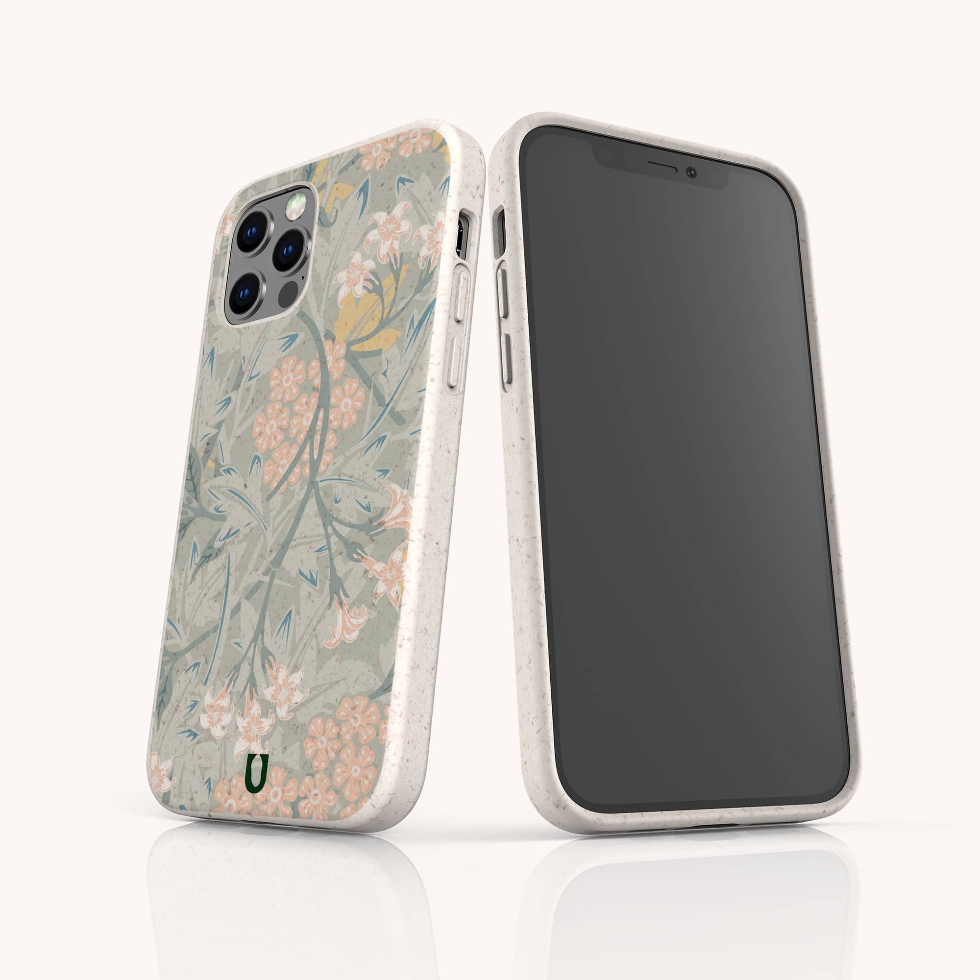 Two smartphones with white, speckled Jasmine Eco-Friendly Phone Cases are shown; one case features pastel floral motifs with green leaves, while the other faces forward with a plain black screen. Both stand upright on a white surface.