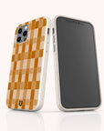 Two smartphones display the Brown Watercolour Checker Eco-Friendly Phone Case—one shows the beige and orange checkerboard design with a white border and small green emblem, compatible with iPhone and Samsung; the other displays the screen.