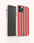 A smartphone in the Red and Pink Stripes Eco-Friendly Phone Case, a beige compostable case with red vertical stripes and a small black horseshoe logo at the bottom, is shown standing upright on a white background.