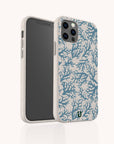 The Blue Coral Eco-Friendly Phone Case is beige with a marine-inspired blue coral pattern and a small green logo at the bottom. Seen upright on a smartphone, it displays both the screen and its biodegradable, decorated back.
