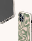 Two smartphones in beige, eco-friendly Green Distorted Lines Phone Cases—one reveals the screen and charging port, the other displays a wavy green and beige pattern. Both cases feature sustainable materials and a natural, speckled texture.