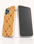 Two smartphones upright on a white surface display the Orange Flower Check Eco-Friendly Phone Case—white speckled with an orange and yellow checkered floral pattern. Compatible with iPhone and Samsung Galaxy; black screens face forward.