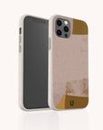 A smartphone with a rear camera is shown in the Caramel Abstract Strokes Eco-Friendly Phone Case, which features beige, pink, gold, and brown designs plus a small green "U" logo for sustainable protection.