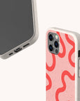 The Red and Pink Swirl Lines Eco-Friendly Phone Case features a biodegradable, beige design with a pink back and wavy red pattern, speckled texture, rounded edges, and is compatible with iPhone and Samsung Galaxy.