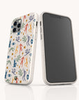 Two Joie de Vivre Eco-Friendly Phone Cases in white, each featuring colorful abstract human figures, eyes, and plant shapes. One phone highlights the artistic case design on its patterned back, while the other displays a blank screen. The background is plain and light.