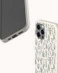 Two smartphones in eco-friendly beige cases: one displays the screen, while the other is fitted with the Green Wild Flowers Eco-Friendly Phone Case, which features a green botanical pattern of small plants and flowers on a white background.