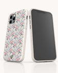 Two smartphones in pastel-accented cases: one displays the back, highlighting the Pink Coquette Flowers Eco-Friendly Biodegradable Phone Case with its vintage-style pink and purple floral pattern, while the other shows the front with a blank black screen. Both cases are white with soft pastel details.