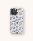 A smartphone featuring the Sea Shells Eco-Friendly Phone Case—a cream-colored accessory adorned with a blue seashell and leaf pattern—displayed against a simple, light background.