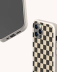 The Black Checker Eco-Friendly Phone Case features a black and beige checkerboard pattern, showcased from angled front and back views against a light background—a stylish and sustainable accessory for your smartphone.