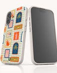 Two smartphones stand upright; one shows a blank screen, while the other displays the Monkey See Monkey Do Eco-Friendly Biodegradable Phone Case, which features a colorful, tropical pattern with palm trees, birds, and geometric windows on a tiled background.