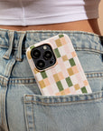 A Pink and Green Watercolour Eco-Friendly Phone Case, made from compostable materials, peeks out of the back pocket of light blue denim jeans worn by someone in a white crop top.
