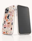 Two smartphones in white speckled cases; one features a blank screen, while the other displays a vibrant, whimsical pattern with mushrooms, hearts, stars, and magical illustrations. Each device is encased in the Love Spell Eco-Friendly Phone Case—offering playful style and sustainable protection for those who value zero-waste living.
