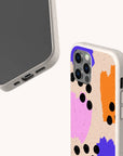 Two smartphones in beige cases; one displays the screen while the other shows the back, featuring the Memphis Eco-Friendly Biodegradable Phone Case with a colorful abstract design of pink, orange, and blue patches accented by scattered black dots on a textured background.