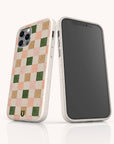 The Pink and Green Checker Eco-Friendly Phone Case features a beige, vegan-friendly design with muted pink, tan, and green checks plus a small horseshoe logo. Compatible with iPhone and Samsung Galaxy devices.