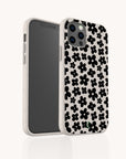 The Black Flower Power Eco-Friendly Phone Case features a white background adorned with a bold black floral pattern. Displayed upright with the screen facing left, the phone case’s striking design stands out against a plain white backdrop.