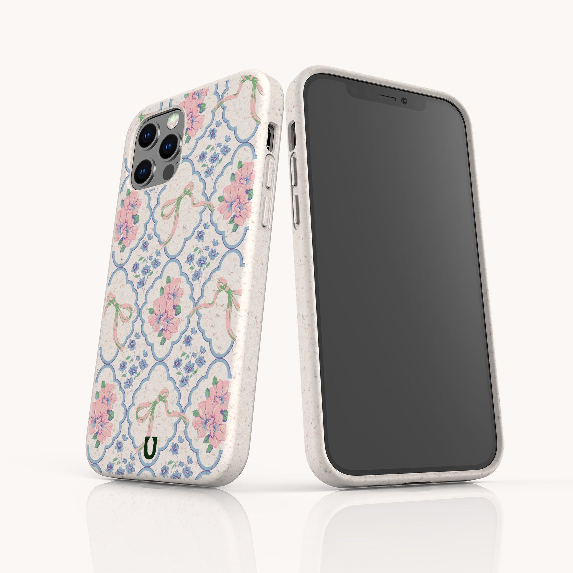 Two smartphones feature the Pink Ribbons Eco-Friendly Biodegradable Phone Case in white with pink floral designs, green accents, and rounded edges; one shows the screen, the other displays the back design on a white surface.