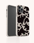 The Cow Print Eco-Friendly Phone Case, shown from front and back on a plain light background, features a speckled white border and full edge coverage. Compatible with iPhone and Samsung Galaxy models.