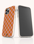 Two smartphones in white-speckled, eco-friendly cases; one shows the front, while the other displays the Orange Checker Eco-Friendly Phone Case’s vibrant orange and pink checkerboard pattern with a small horseshoe-shaped logo at the bottom.