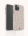 The Red Hearts Eco-Friendly Phone Case in beige, decorated with small red hearts, is shown from front and back to display the heart design and camera cutout. Compatible with iPhone and Samsung Galaxy models.