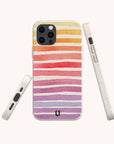 The Summer Rainbow Eco-Friendly Phone Case features uneven horizontal stripes in red, orange, yellow, pink, and purple on a light beige background. Made from compostable materials. Shown from back, side, and bottom; compatible with iPhone and Samsung.