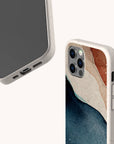 Two smartphones in beige Watercolour Landscape Eco-Friendly Phone Cases; one displays the screen and charging port, the other shows a blue, white, and brown abstract design by the camera. Both compostable cases are set against a light background.
