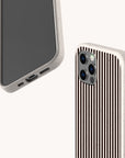 Two smartphones with beige cases rest on a plain white background; one displays its screen and charging port, while the other showcases the Thin Black Stripes Eco-Friendly Phone Case, featuring a grooved brown vertical striped pattern and visible camera lenses.
