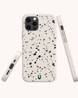 The Black Terrazzo Eco-Friendly Phone Case is shown from the back, side, and bottom against a light background. This compostable case features a terrazzo pattern and precise cutouts for the camera, buttons, and ports.