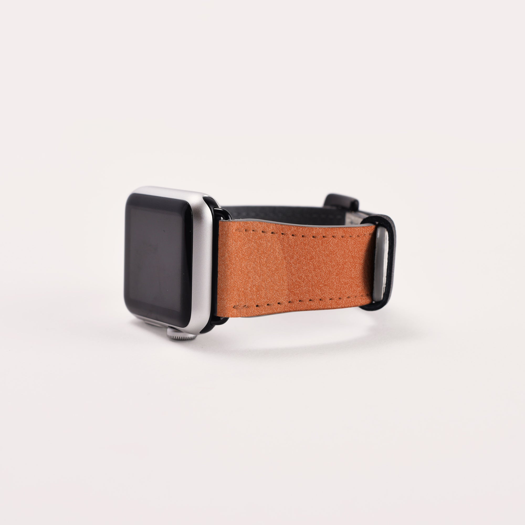 The Abstract Cut Out III Vegan Leather Apple Watch Band boasts a silver frame with a black screen and is paired with a brown vegan leather strap. This cruelty-free band features a smooth texture and is secured by a sleek black buckle, all elegantly displayed on a plain white background, emphasizing both sophistication and sustainability.