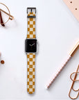 An Apple Watch featuring the Terracotta Checker Vegan Leather Band sits on a desk surrounded by a notebook, pen, glasses, large paperclip, and a polka-dotted notepad.