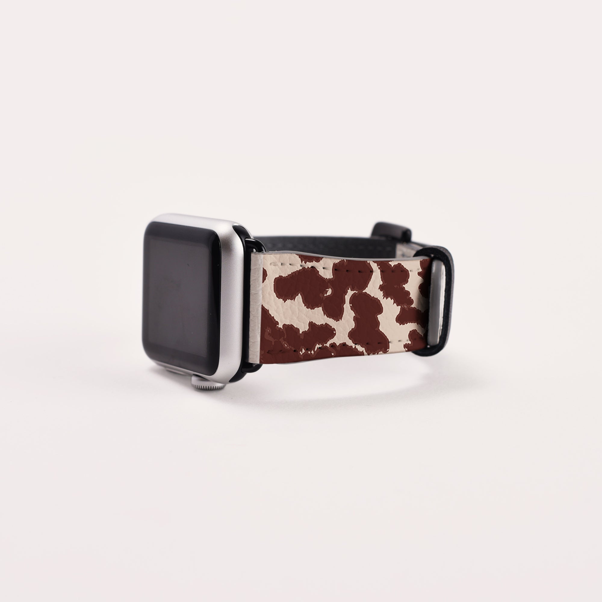 The Brown Cow Vegan Leather Apple Watch Band with a black frame exudes rustic charm against a plain white background.
