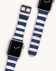 Displayed on a light background are two smartwatches with navy blue and white striped bands known as the Navy Stripes Vegan Leather Apple Watch Band. Each watch showcases a simple clock face with a black background and yellow minute markers, highlighted by eco-conscious bands that include metallic buckles.