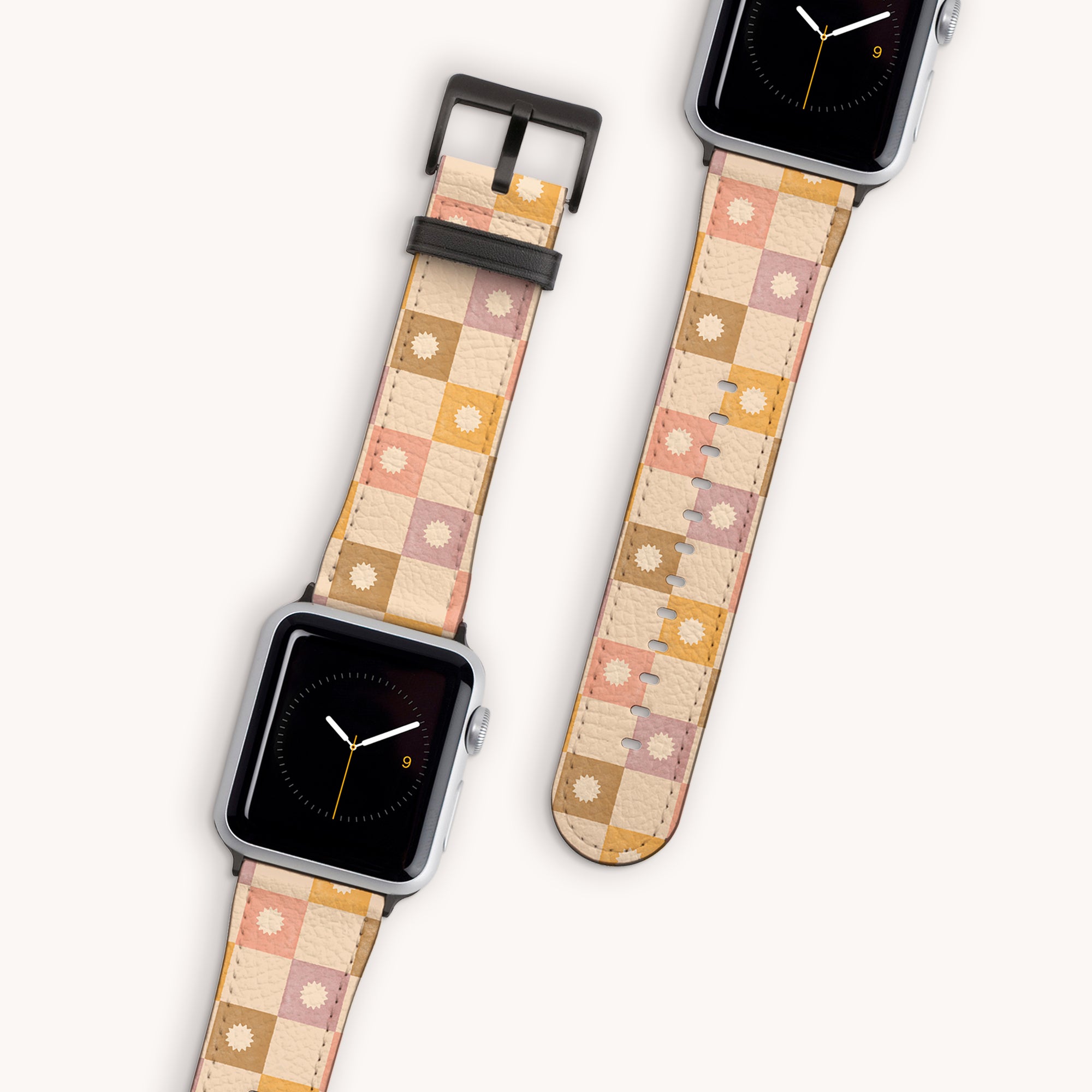 Two smartwatches feature the Star Pink Check Vegan Leather Apple Watch Bands, showcasing a patchwork design of pink, beige, and orange squares along with floral motifs. These bands are crafted from vegan leather to ensure style meets sustainability. The watch faces show the time as the bands lay flat to highlight their design.