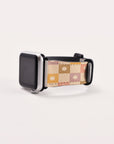 Displayed is the Star Pink Check Vegan Leather Apple Watch Band with a square black screen. The band sports a beige, pink, and cream checkered pattern adorned with small floral designs, against a plain white background.
