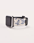 The Turtles Vegan Leather Apple Watch Band is an eco-friendly smartwatch strap in white and blue with a turtle design. It features a black watch face and partially looped strap set against a plain white background.