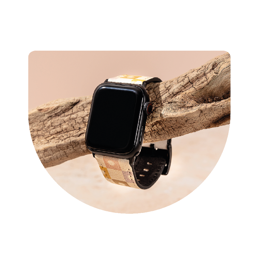 An apple watch with a vegan leather band hanging on a tree branch