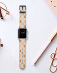 A Pink Checker Vegan Leather Apple Watch Band sits on a desk with office supplies—like a notebook, pen, paper clip, and glasses—adding style and sustainability to your essentials.