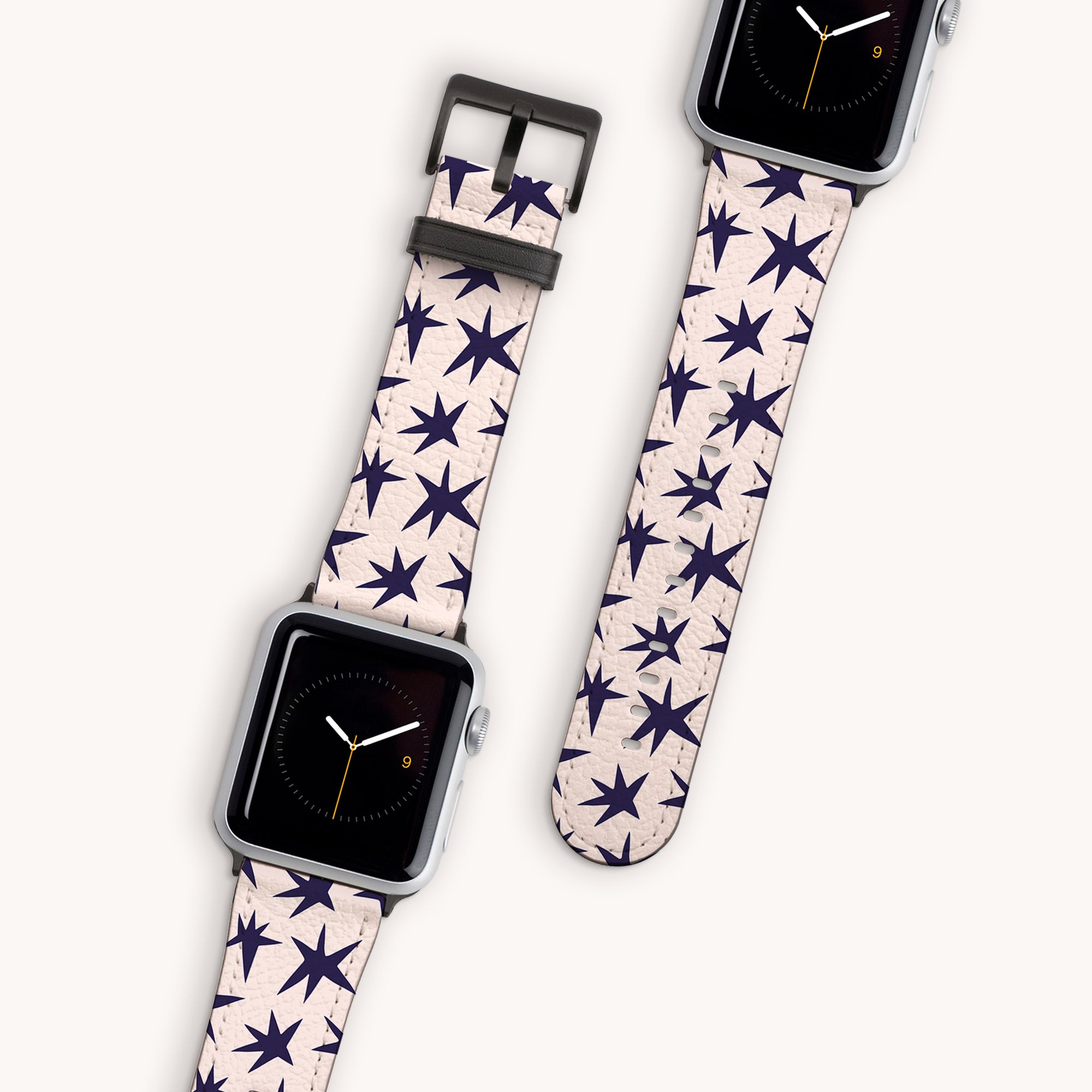 The Wonky Stars Vegan Leather Apple Watch Band set features two smartwatches with vegan leather straps, adorned with black star patterns. The watch faces have a simple clock design with orange hands on a black background, against a light gray backdrop, ideal for any collection.